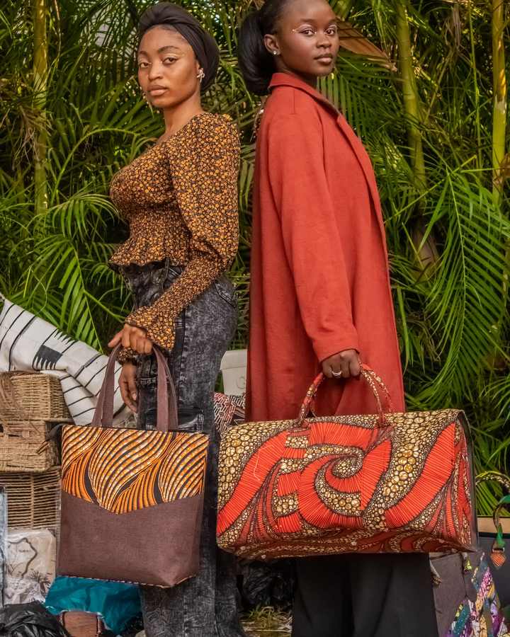 Deux femmes présentant des sacs en tissu wax dans un décor de plantes tropicales